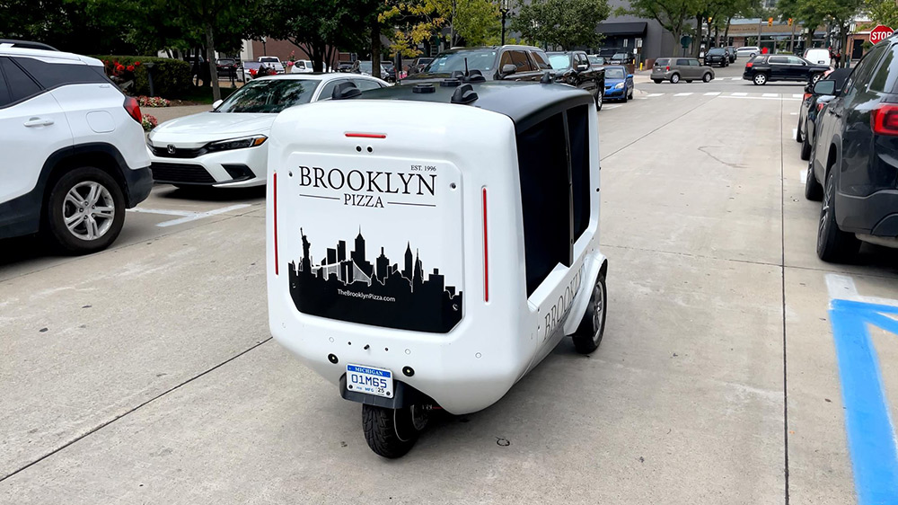 Two people standing in front of a building with electric two-wheelers.