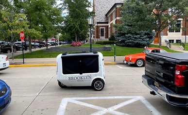 Two people standing in front of a building with electric two-wheelers.