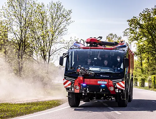 Fire truck driving along a tree lined road