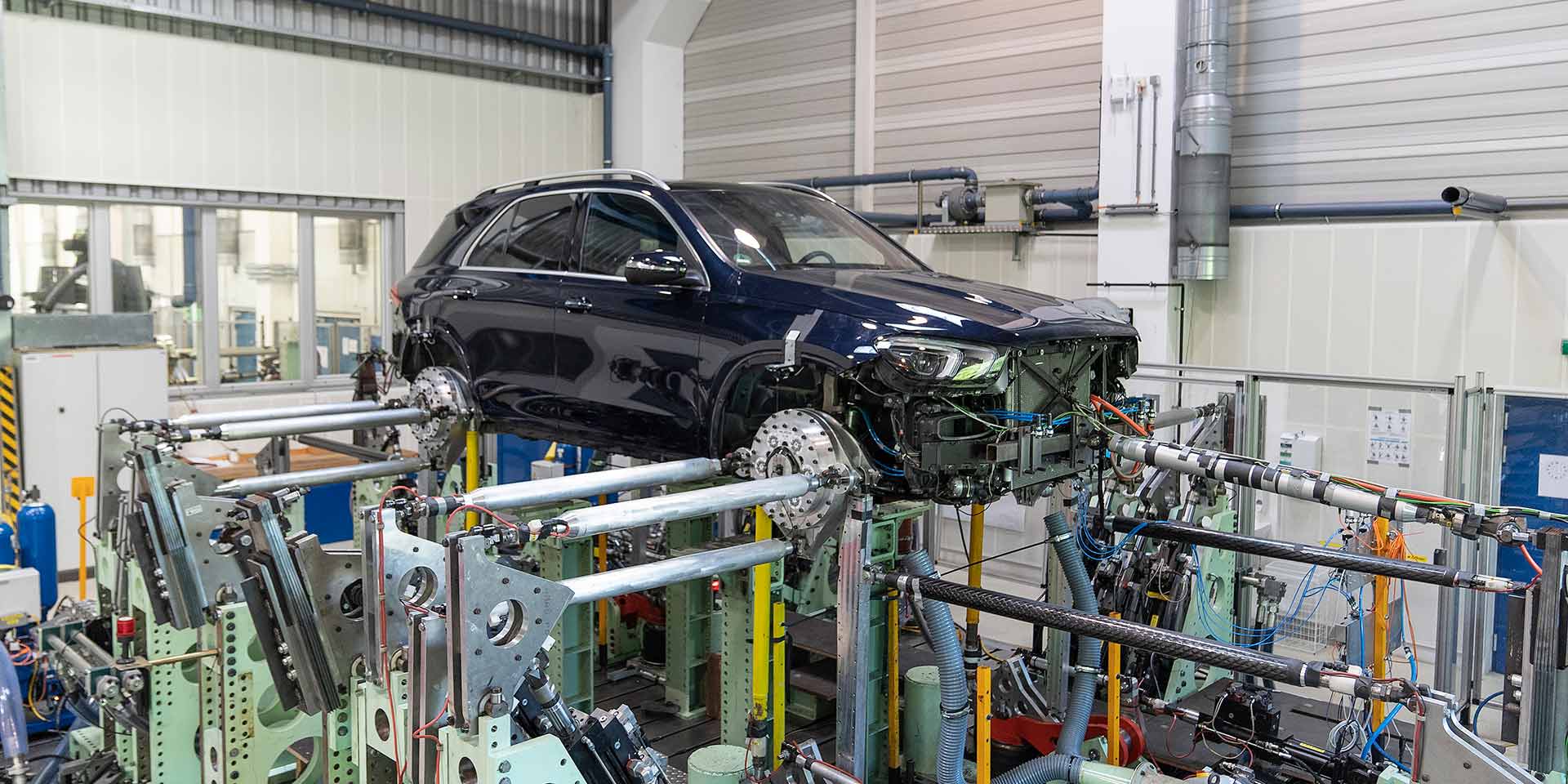 Car body mounted on an automotive assembly line with metal fixtures and machinery surrounding it.