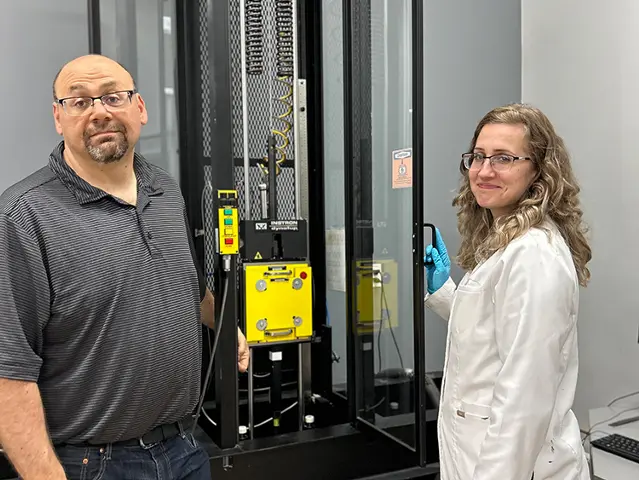 Two team members standing next to a machine in a testing facility