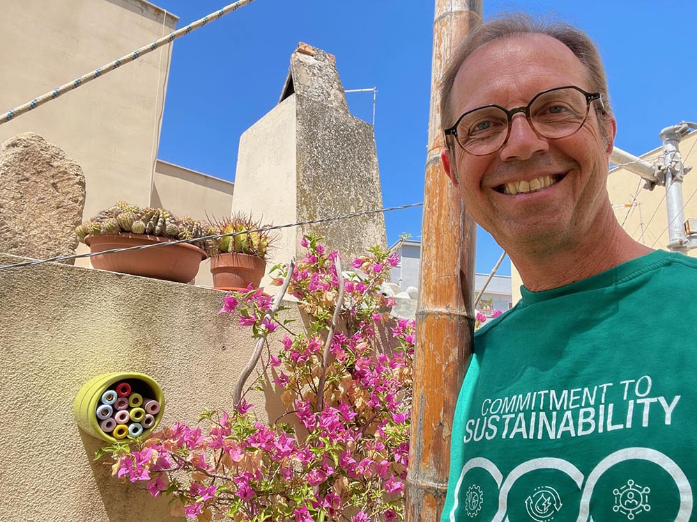 Frank Hoffmann with a bee hotel attached to a wall