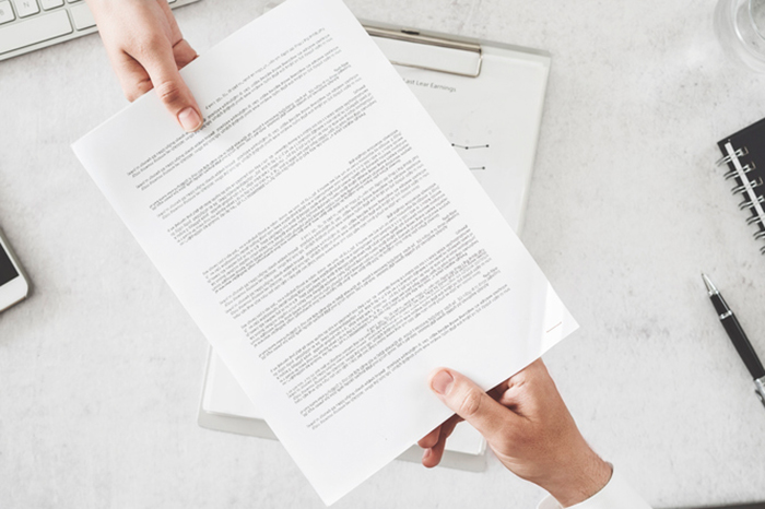 Two people exchanging a document over a desk